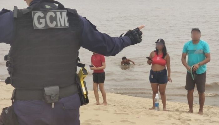 Descumprindo interdição, grupo de banhistas é orientado a sair da praia da Ponta Negra na extrema vazante do rio￼